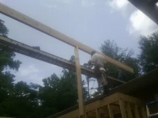 Carpenter setting a ridge beam over a new addition frame — Ice Dam Removal by Roofing Brothers in Carolina
