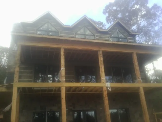 Dormers and porch framing on a large log home under construction — Roof Coating work by our crew in Carolina