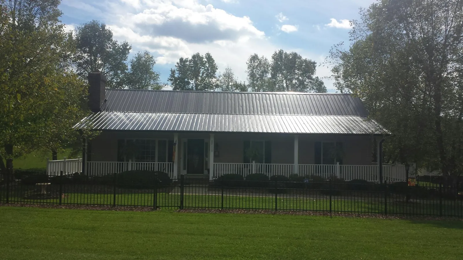 Gray metal roof on a brick ranch with a full width front porch — Gutter Guard Installation work by our crew in Carolina