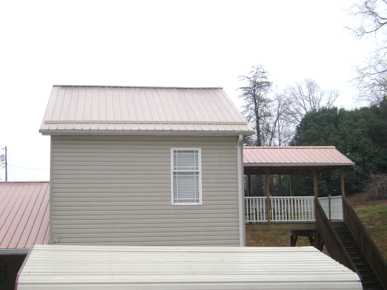 Tan metal roofs on a two story addition and attached porch, from a Roof Replacement job in Carolina