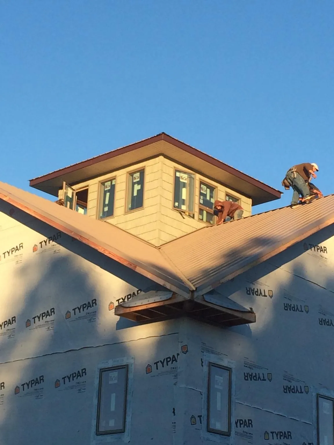 Roofers working around a rooftop cupola on a new metal roof at sunset — Roof Waterproofing in Carolina by Roofing Brothers